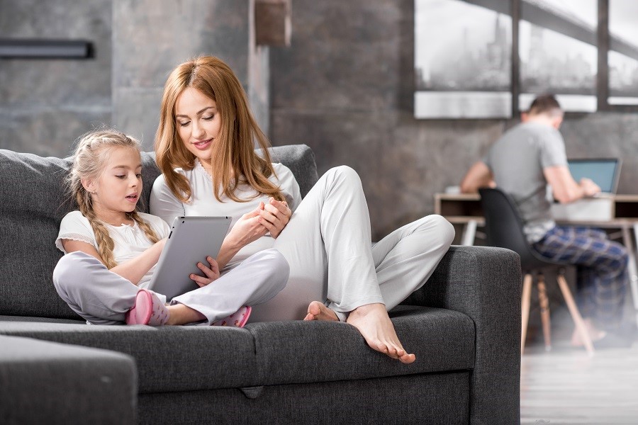 Mother and daughter controlling their home from the living room couch