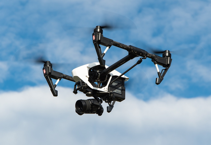 Drone flying with a security camera attached to the bottom